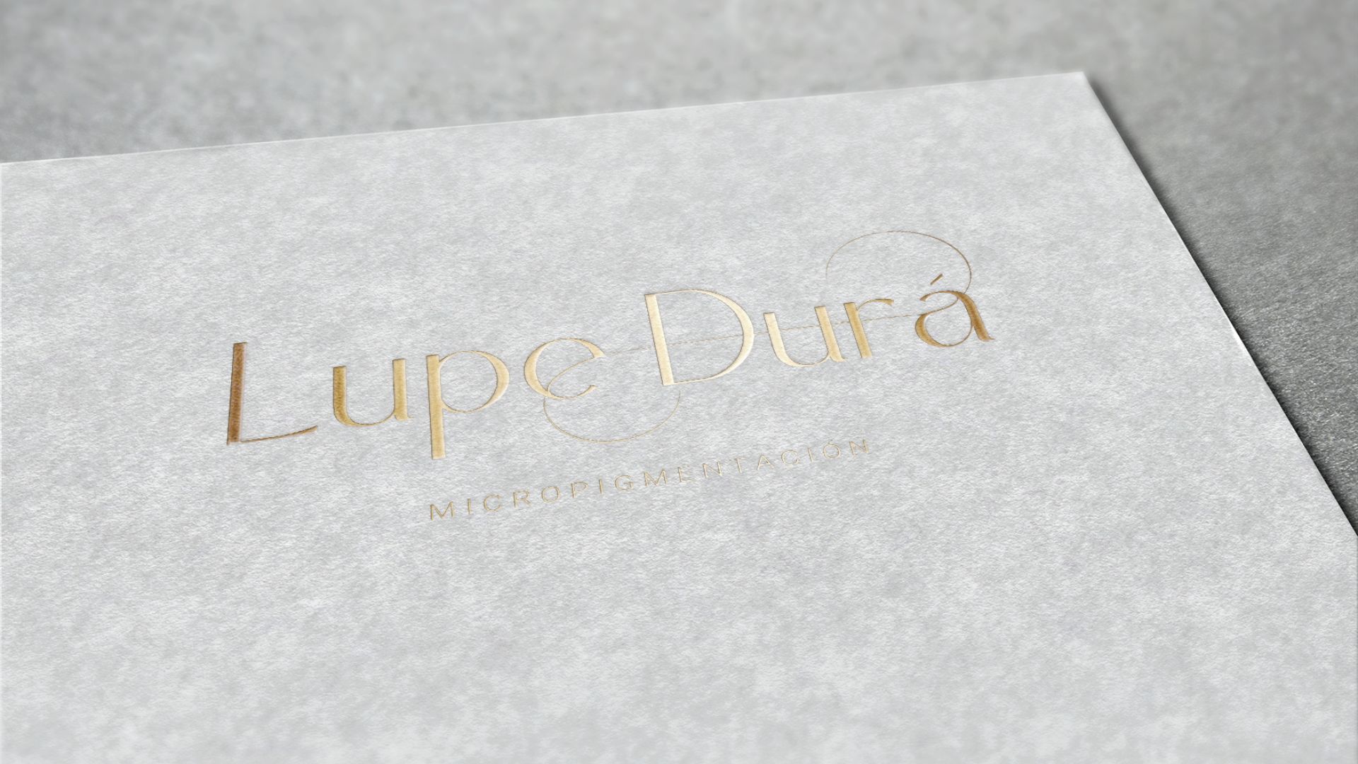 Identidad visual de Lupe Durá en dorado sobre fondo gris